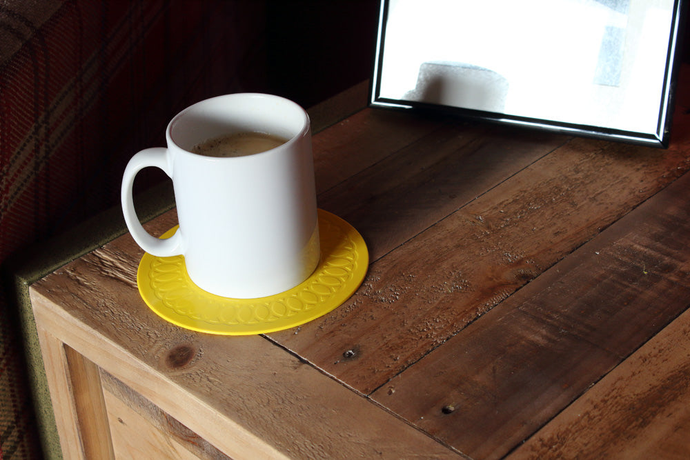 yellow coaster on table with coffee cup