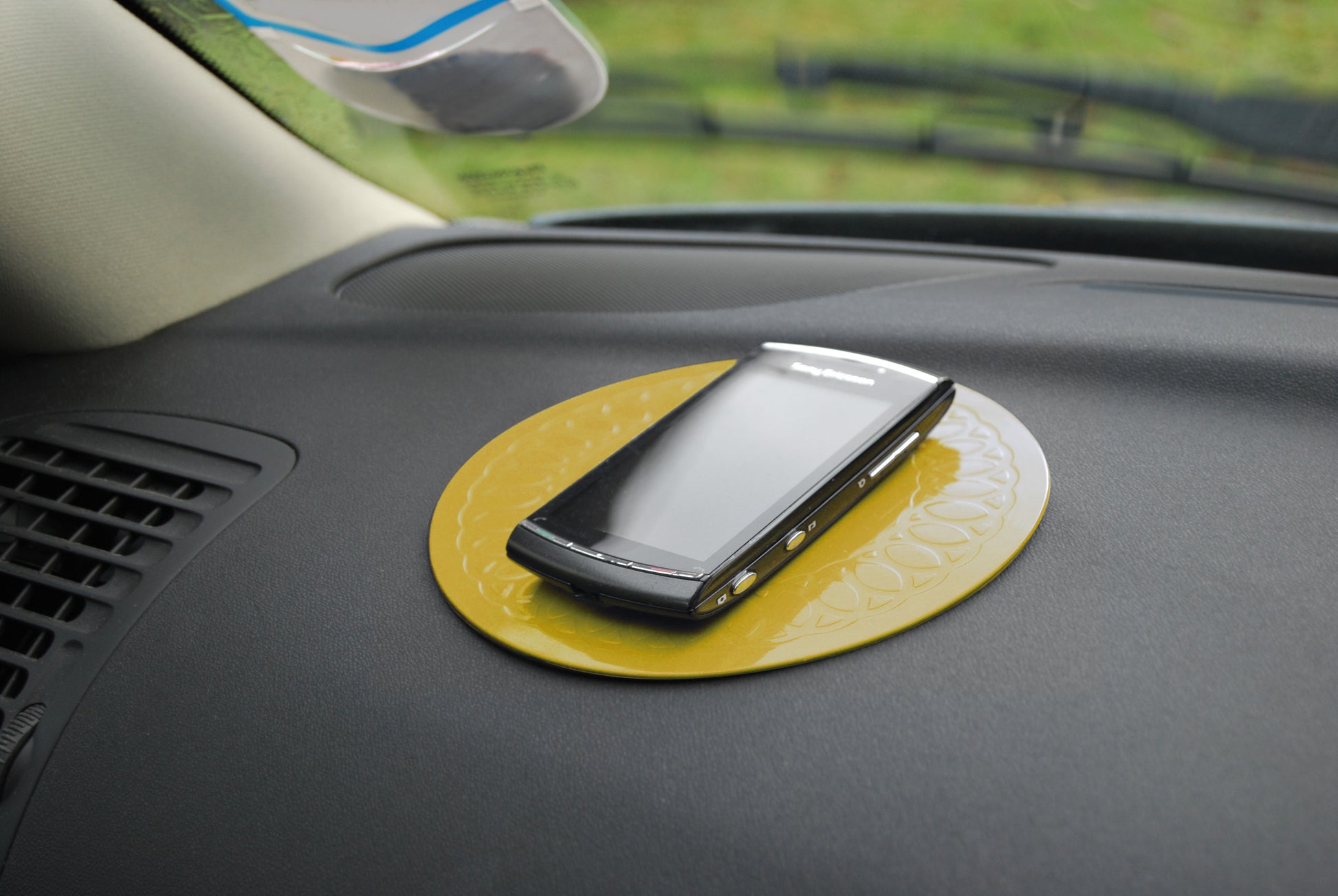 anti-slip yellow coaster on dash of car with cell phone on coaster